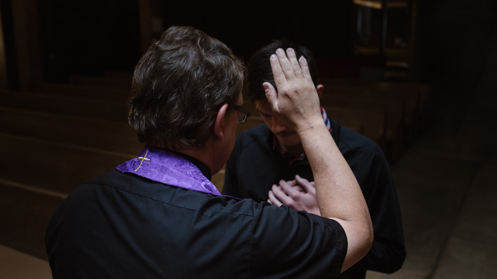 priest touching man's forehead